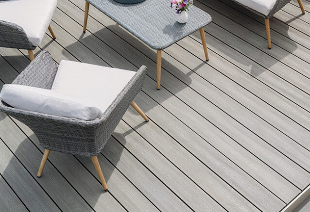 A pale grey timber decking area with neatly arranged garden furniture.
