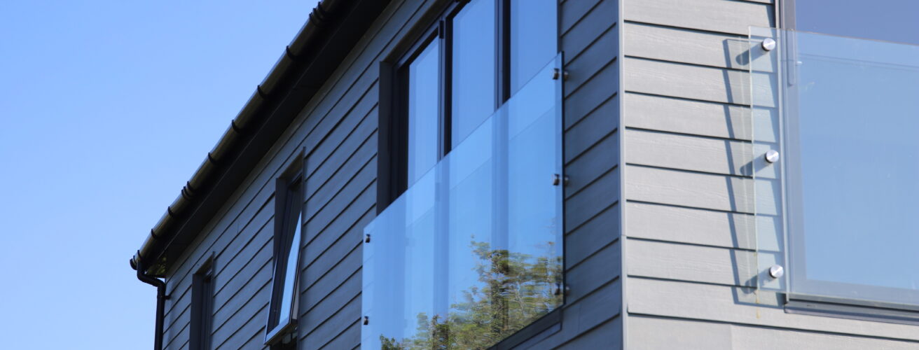 Horizontally-laid Hardie® Plank on a holiday cabin with balconies set against a clear blue sky. From Bluestone, Wales.