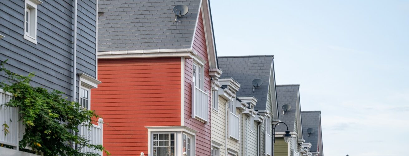A row of colourful multi-storey homes featuring Hardie Plank cladding in blue, red, white and green.