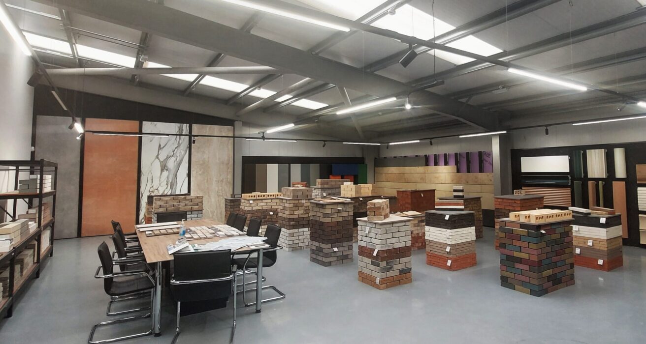An image of a construction display studio, with cladding examples on the walls, brick podiums, tables and chairs.