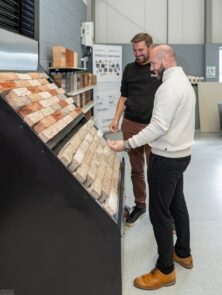 Two people smiling and looking at a brick display.