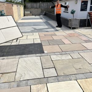 A person in an orange hi-viz jacket standing in an outdoor landscaping display.
