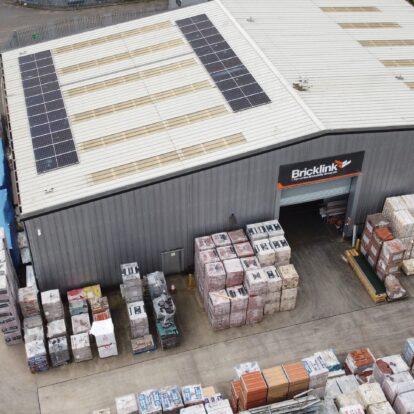 An aerial view of a brickyard with large warehouse with solar panels on the roof.