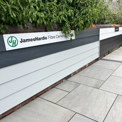 An image of Hardie Plank panels displayed on a low brick wall with porcelain paving on the ground in front.