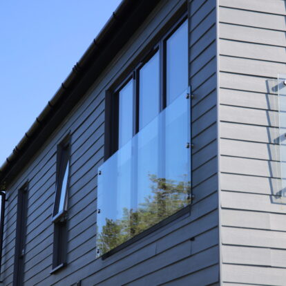 Horizontally-laid Hardie® Plank on a holiday cabin with balconies set against a clear blue sky. From Bluestone, Wales.
