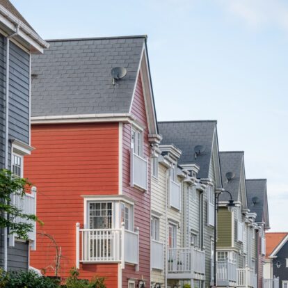 A row of colourful multi-storey homes featuring Hardie Plank cladding in blue, red, white and green.