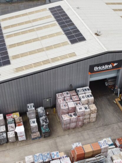 An aerial view of a brickyard with large warehouse with solar panels on the roof.