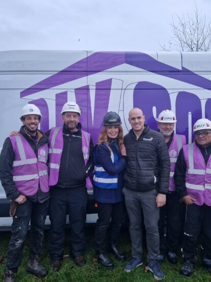 A man wearing a Brickability jacket stands with six members of the DIY SOS team in front of a DIY SOS van.