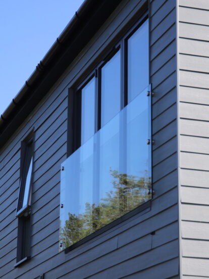 Horizontally-laid Hardie® Plank on a holiday cabin with balconies set against a clear blue sky. From Bluestone, Wales.