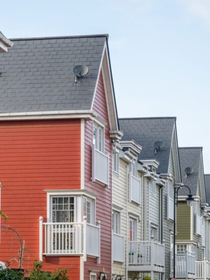 A row of colourful multi-storey homes featuring Hardie Plank cladding in blue, red, white and green.