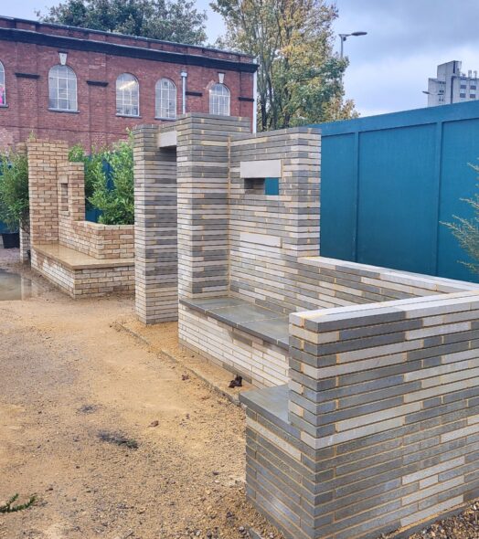 Two stone structures made of stone bricks, set among an outdoor building site waiting to be landscaped.