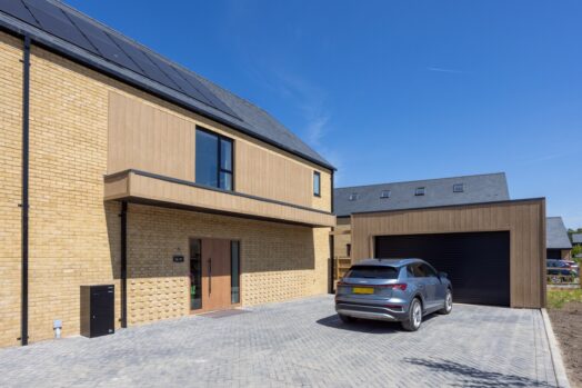 A large, modern house with timber-effect cladding details and brickwork patterns by the front door.