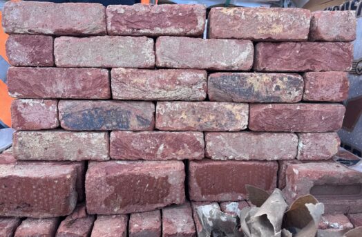 A small wall made from textured red multi bricks.