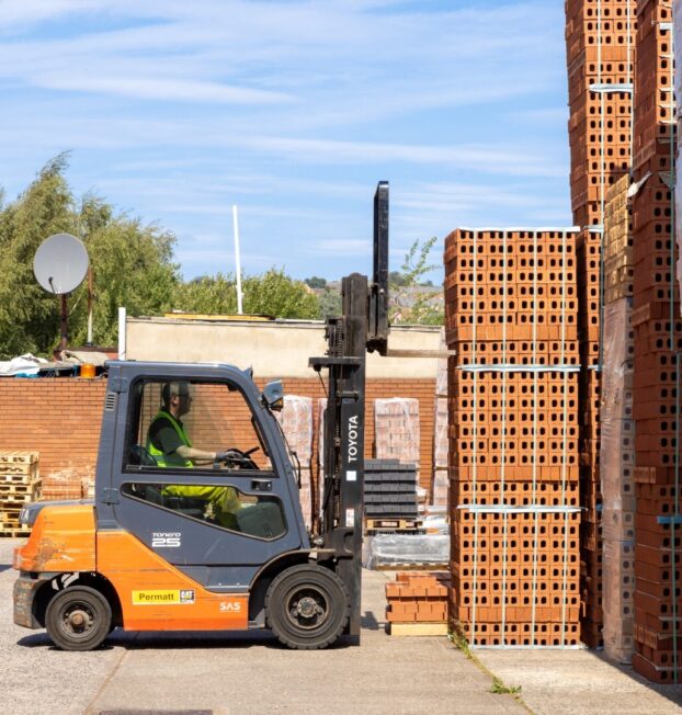 An image of a forklift truck lifting stacks of bricks.