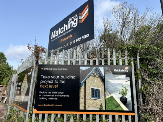 A selection of signs displayed above and on a metal fence. The signs display the products on offer from Brickability Matching Brick.