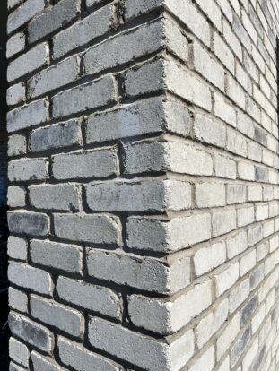 The corner of a building displaying light grey bricks.