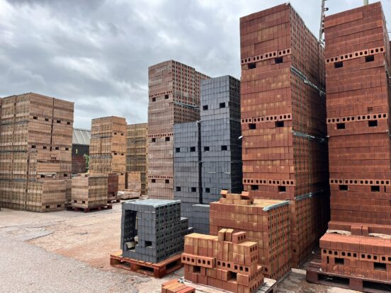 Several large stacks of buff, dark and red bricks.