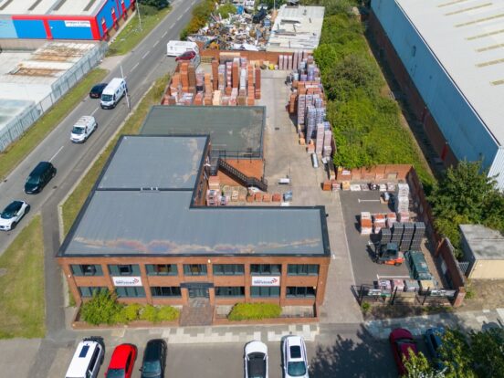 An aerial view of a building with large stacks of bricks in the yard.
