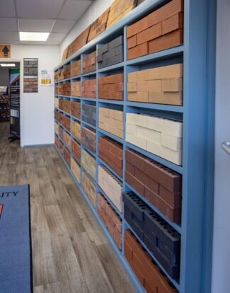 A wall of dark grey shelves displaying different types and colours of bricks.