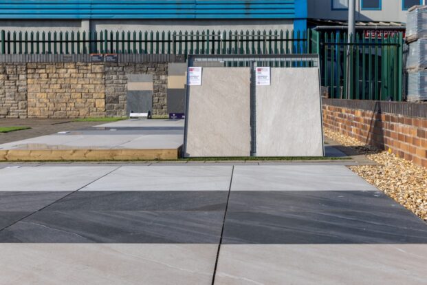 A small area of porcelain paving with two additional slabs propped up at the back in a display.