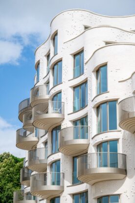 White glazed facade of an apartment block with a waved shape.