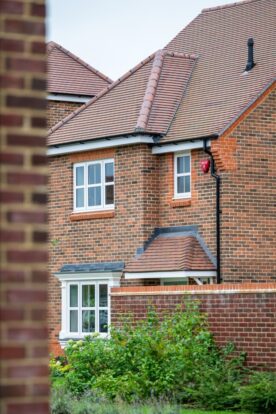 Photo of a house taken next to a brick wall in the foreground.