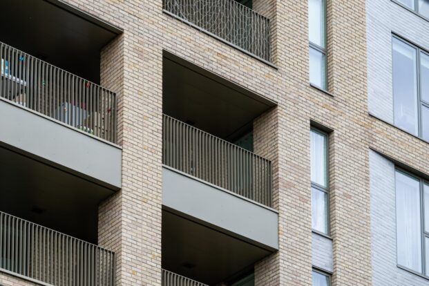 A photo of the side of an apartment block with buff bricks and balconies.