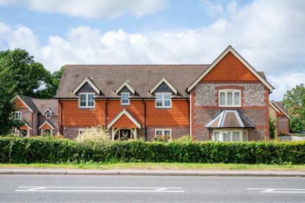 A grand house featuring a red slate and knapped flint block facade.