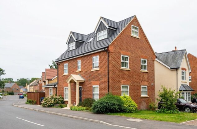 Red-brick house with cream-coloured pillars, set in a housing estate.