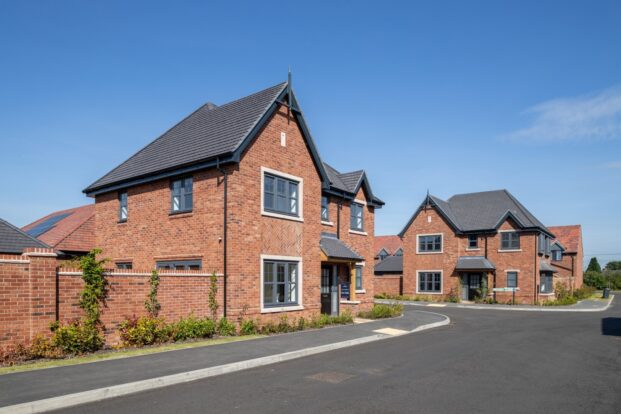 A housing estate with grand red-brick houses featuring dark slate roofs.