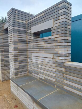grey and white linear bricks made of stone with grey stone slab for seating