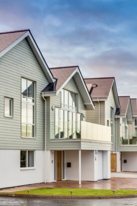 A row of coastal houses featuring soft green timber-effect cladding.