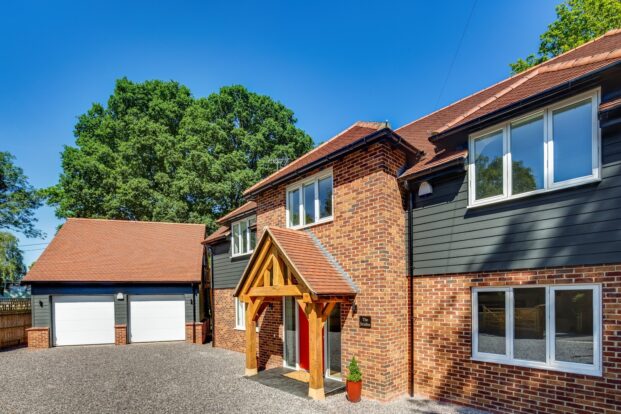 A brick house with the first floor clad in blue boards.