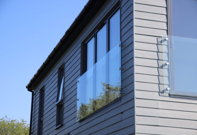 Horizontally-laid Hardie® Plank on a holiday cabin with balconies set against a clear blue sky. From Bluestone, Wales.