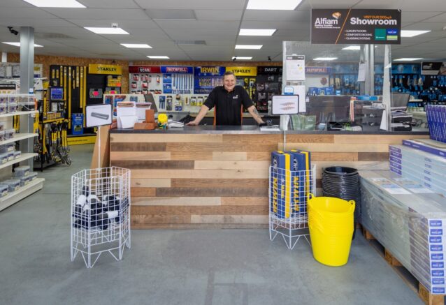 A smiling man standing behind the front desk at a builders merchant.
