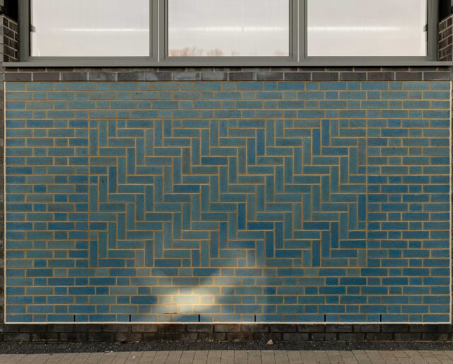 A blue brick panel on a dark brick wall.