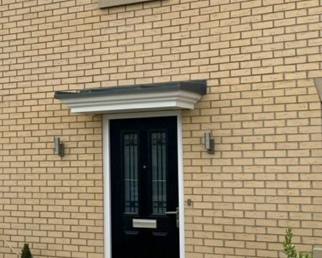 A photo of the front door of a buff brick house.