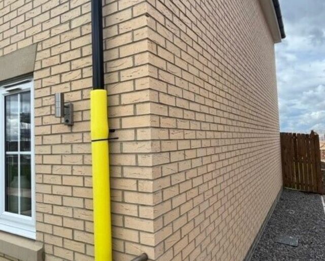 The corner of a house built from buff-coloured bricks.