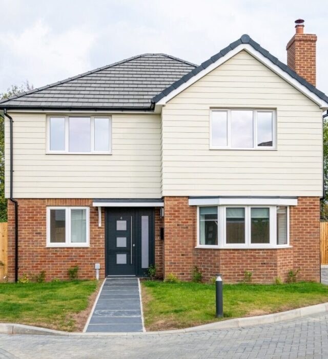 A photo of a two-storey house with red brick ground floor and white timber-effect cladding wrapping the first floor.