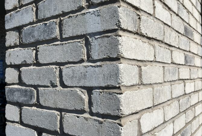 The corner of a grey, concrete brick building.