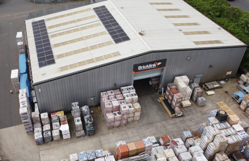 An aerial view of a brickyard with large warehouse with solar panels on the roof.