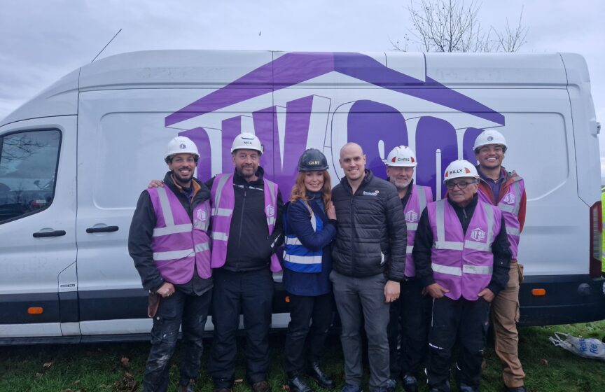 A man wearing a Brickability jacket stands with six members of the DIY SOS team in front of a DIY SOS van.