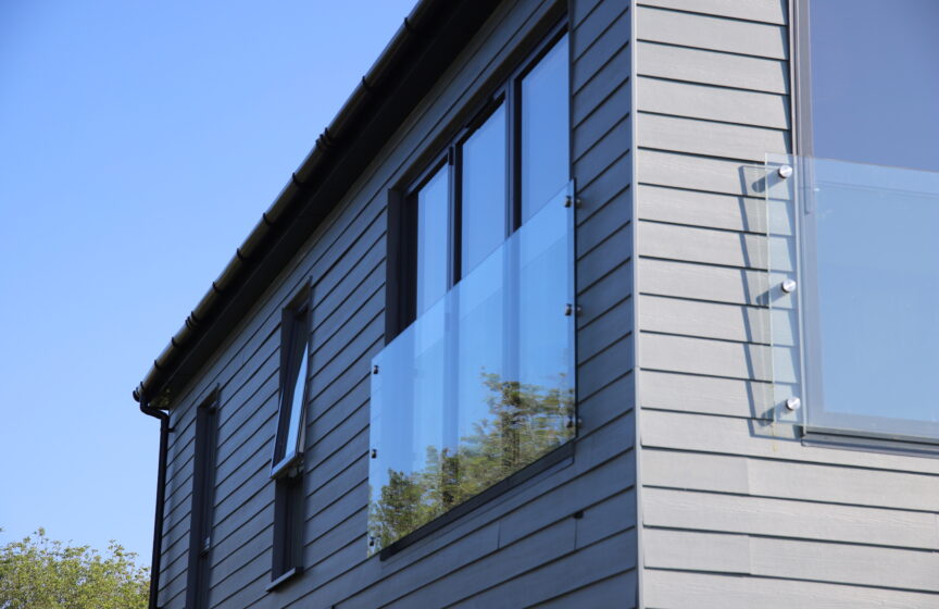 Horizontally-laid Hardie® Plank on a holiday cabin with balconies set against a clear blue sky. From Bluestone, Wales.