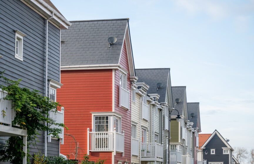 A row of colourful multi-storey homes featuring Hardie Plank cladding in blue, red, white and green.